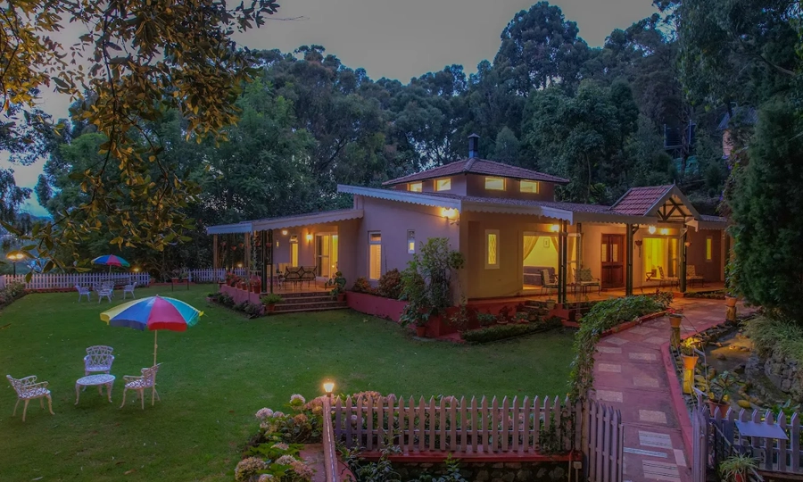 Relax on the green lawn by this warm lit villa surrounded by trees and outdoor seating Rayne Forest Kotagiri