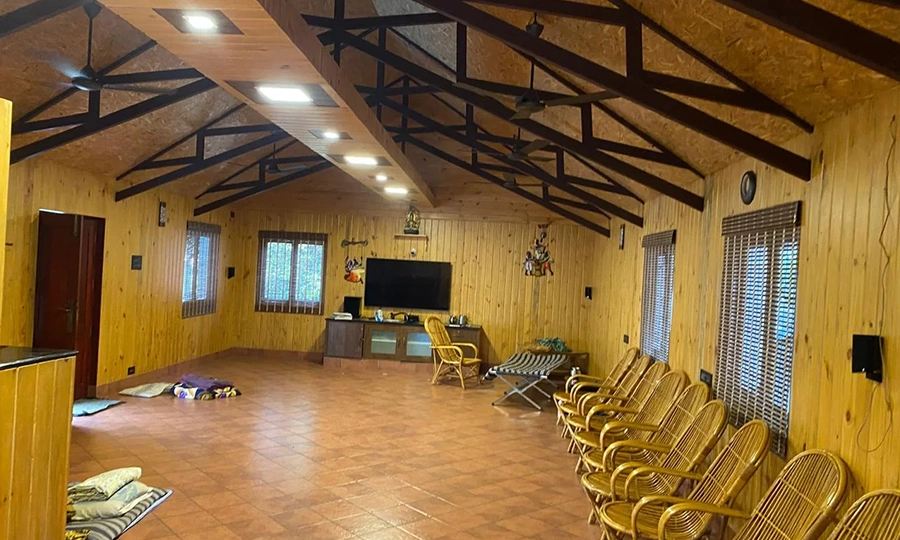 Relax in a large, well-lit living hall featuring cozy wooden décor at a private farmhouse stay Sulur.