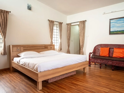 Unwind in a cozy homestay bedroom offering soft linens, fresh breeze, and calm ridge scenery in Kotagiri.