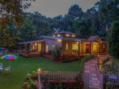 Relax on the green lawn by this warm lit villa surrounded by trees and outdoor seating Rayne Forest Kotagiri